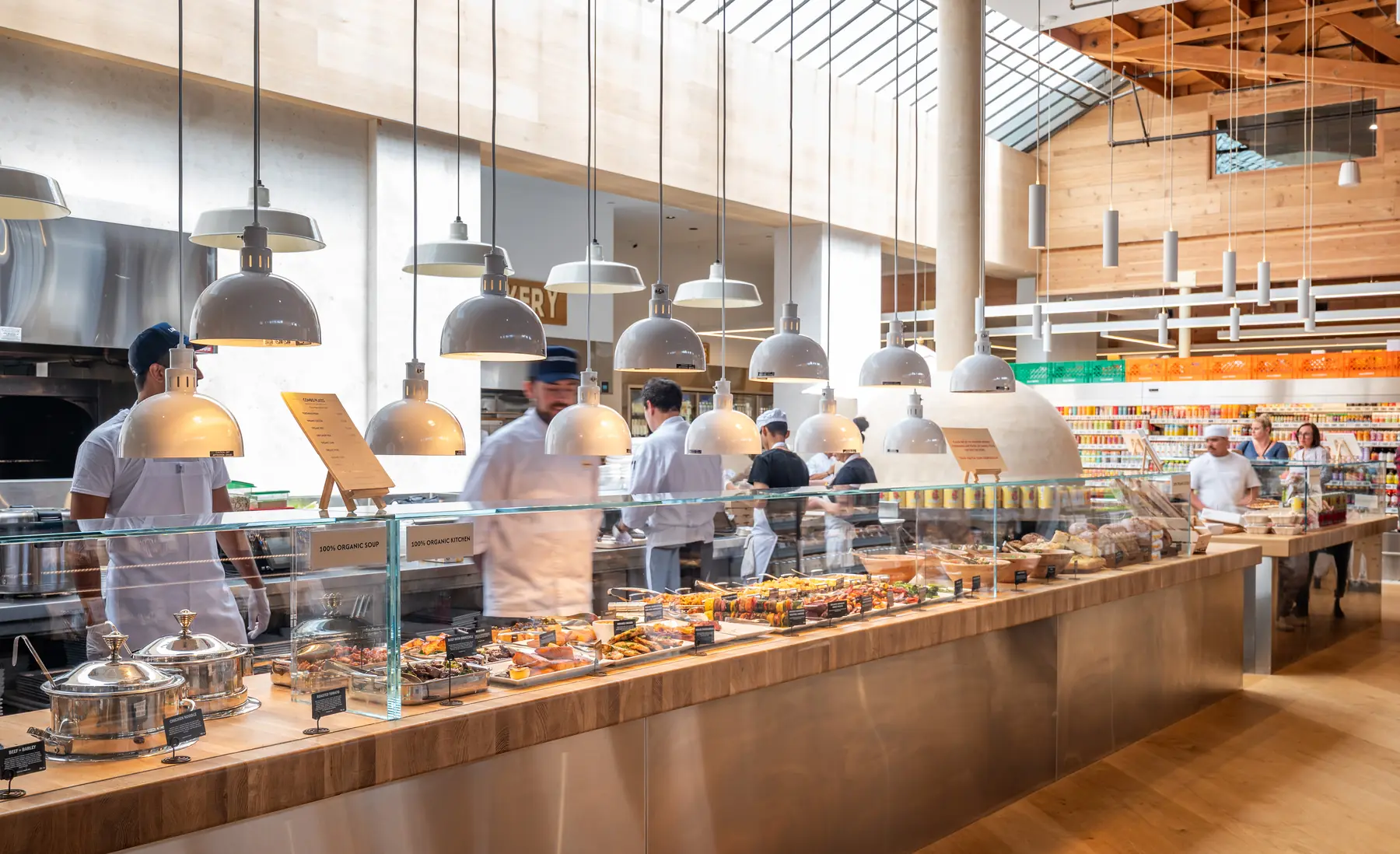 Chefs working behind the long hot bar counter under pendant lights
